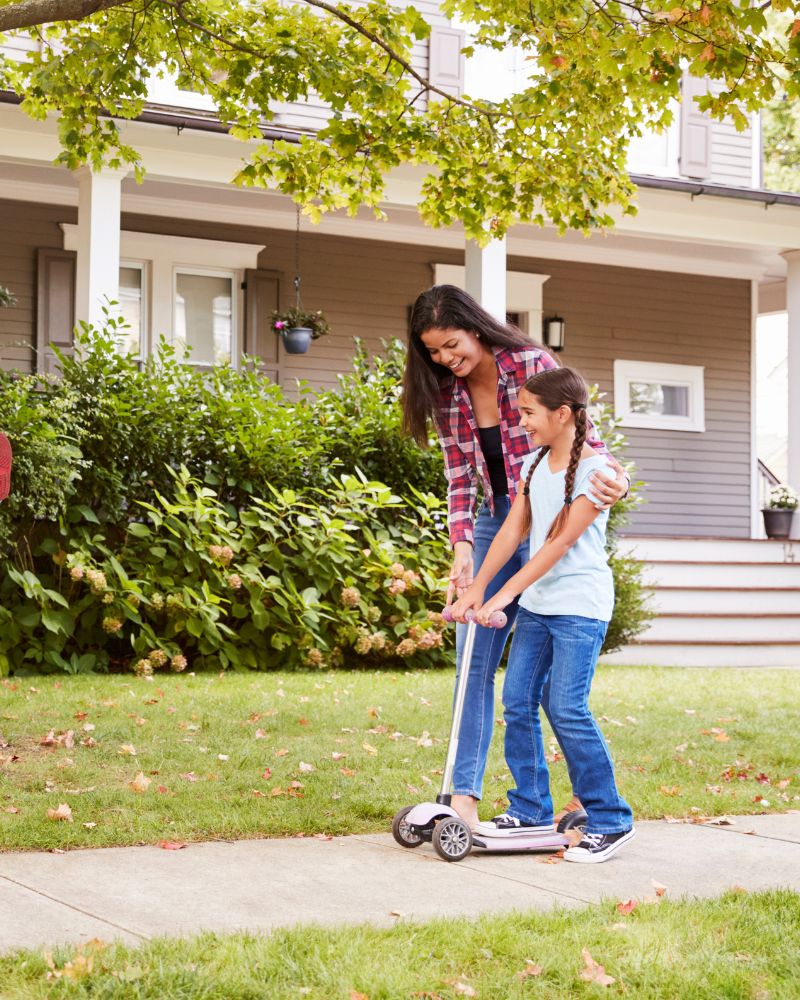 Daughter playing on scooter while mom guides her